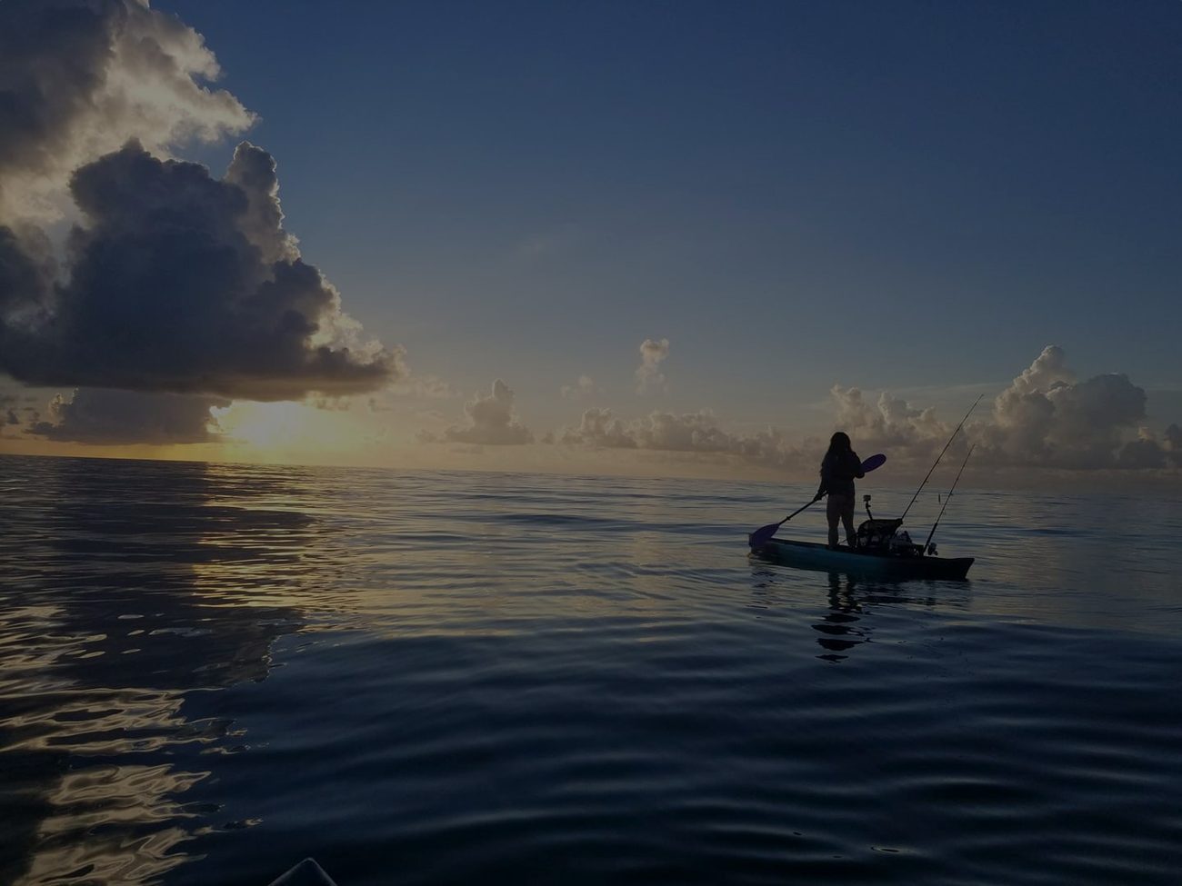 Standing and casting from a NuCanoe on glassy water at sunset